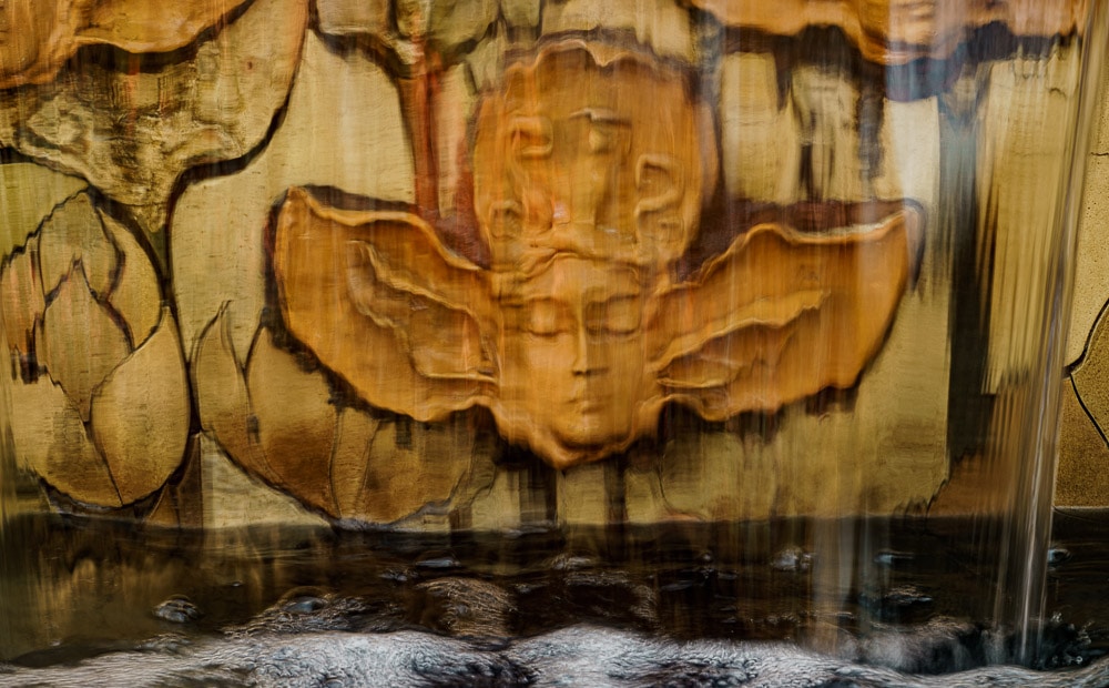 Water naiads are represented in bas relief peering out from behind the waterfall
